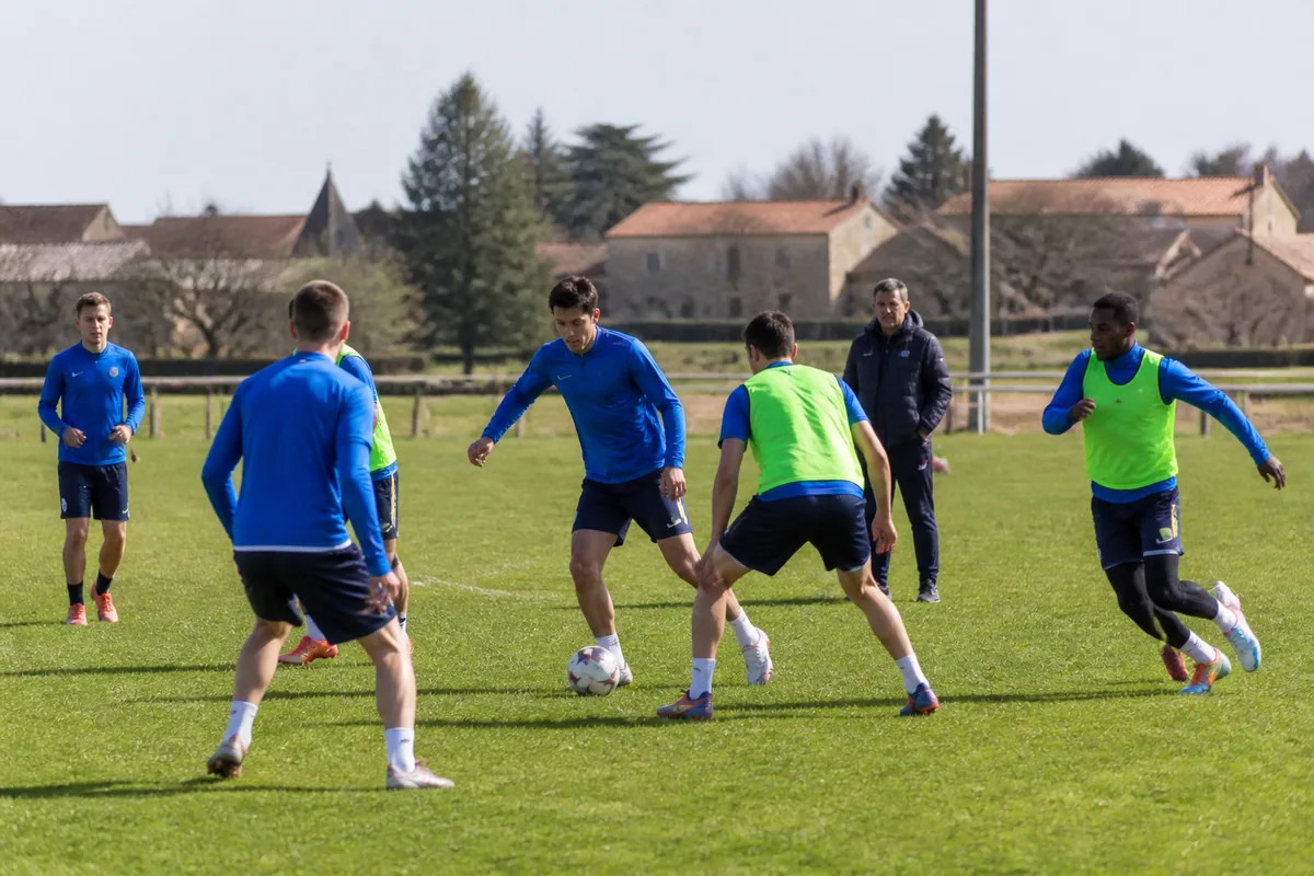 Entraînement de football amateur avec joueurs et coach sur terrain gazonné